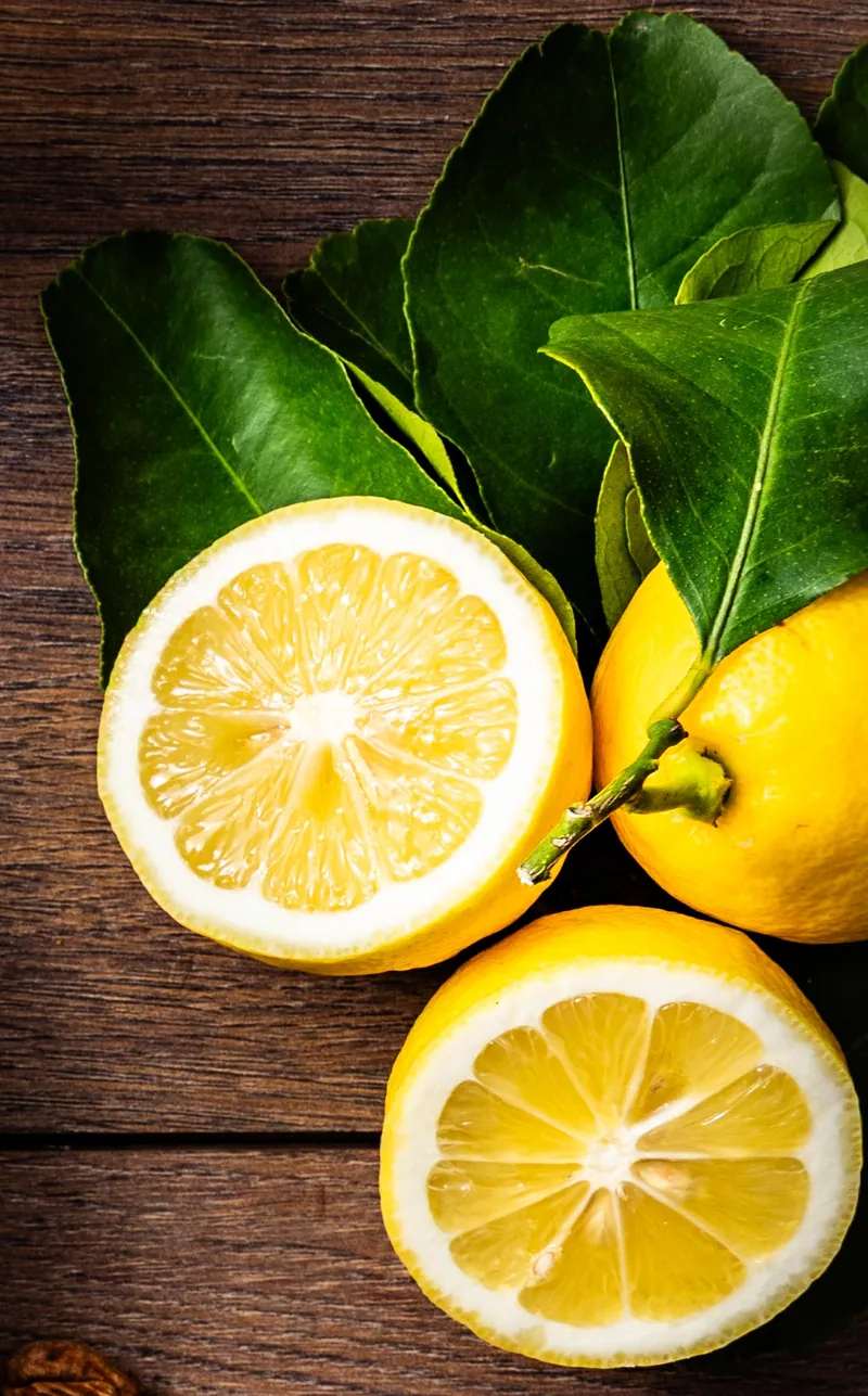 Des citrons entiers et coupés, avec leurs feuilles